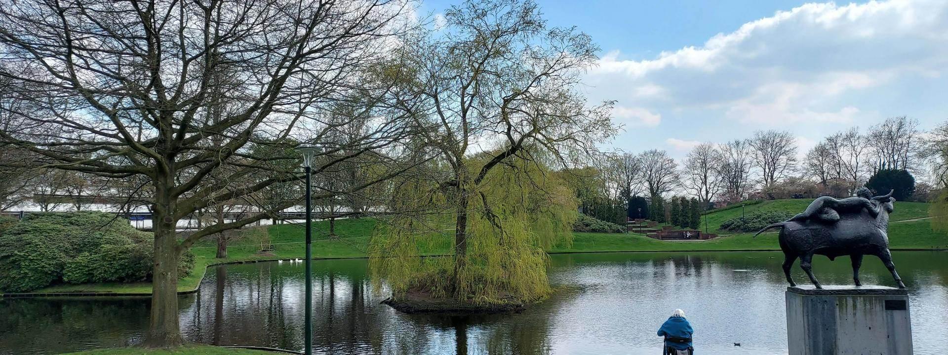 foto van park met water, bomen en een standbeeld
